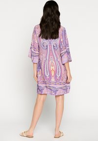 Violetilla kaftan-mekko, jossa on kellohihat ja polviin ulottuva leikkuu. Materiaali vaikuttaa kevyeltä ja siinä on valuva muotoilu.