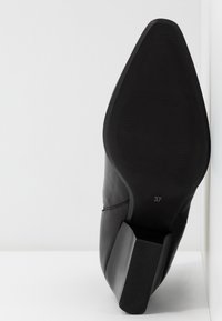 Schwarze Lederstiefelette mit spitzer Zehenpartie und niedrigem Blockabsatz. Glattes Obermaterial mit strukturiertem Absatzakzent, Größe 37 auf der Sohle angegeben.