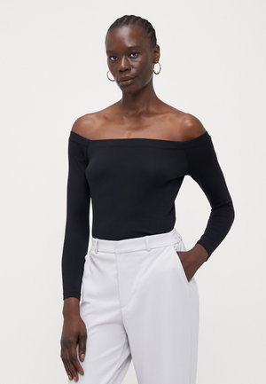 Schwarzer Off-Shoulder-Bodysuit mit langen Ärmeln aus glattem Stoff; kombiniert mit hellgrauen high-waisted Hosen; minimalistisches Design.