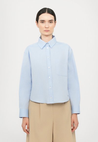 Chemise boutonnée bleu clair avec un col classique, manches longues, poche poitrine unique et un ourlet court, fabriquée en tissu lisse.