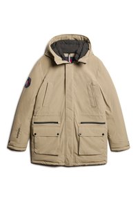 Parka aislante beige con capucha desmontable, doble bolsillo frontal, bolsillos laterales con cremallera y logo en la manga izquierda. Textura de tejido suave.