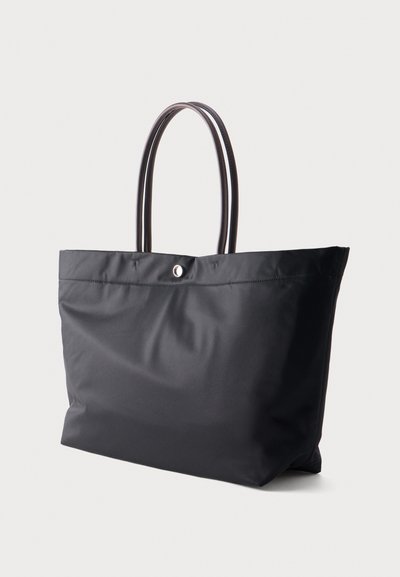 Sac cabas noir avec double poignée en cuir et fermeture par un bouton unique en haut, présenté sur un fond uni.