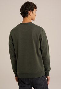 Sudadera verde oscuro con cuello redondo, mangas largas, puños y dobladillo de canalé, que presenta una tela texturizada. Muestra la vista trasera.