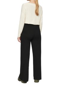 Crème lange mouw top met een cropped fit, gecombineerd met hoge taille, rechte zwarte broek. De outfit heeft een zachte textuur en een eenvoudig ontwerp.