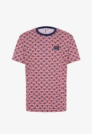 T-shirt a righe rosse, bianche e blu con scollo rotondo, maniche corte e un patch con logo. Il design presenta forme geometriche ripetitive.