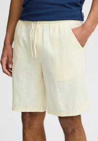 Lichtbeige linnen shorts met een elastische tailleband en trekkoord, voorzien van zijzakken en een ontspannen pasvorm. Gladde textuur en casual ontwerp.