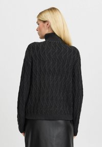 Schwarzer gestrickter Pullover mit einem strukturierten Rautenmuster, hohem Kragen und gerippten Bündchen und Saum. Lange Ärmel und lockere Passform.