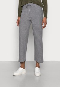 Culottes grises côtelées en tissu doux, dotées d'une taille à cordon de serrage et d'une longueur raccourcie, associées à des baskets blanches.