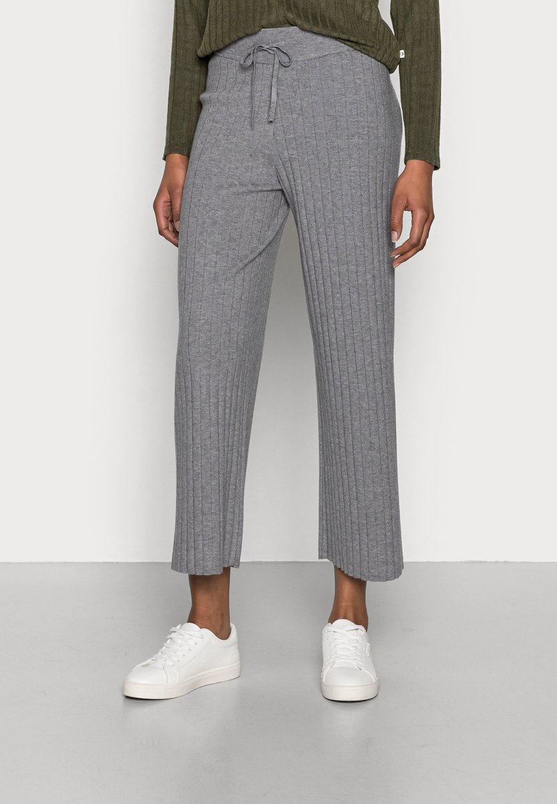 Culottes grises côtelées en tissu doux, dotées d'une taille à cordon de serrage et d'une longueur raccourcie, associées à des baskets blanches.