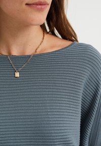 Niebieski prążkowany top z szerokim dekoltem, charakteryzujący się gładką teksturą i lekkim połyskiem, w połączeniu ze złotym naszyjnikiem z zawieszką.