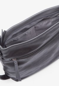 Sac bandoulière en cuir noir avec un zip sur le dessus, des compartiments intérieurs et une poche latérale. Texture lisse avec un design minimaliste.