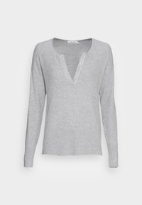 Light gray ribbed sweater with a deep V-neck, long sleeves, and a relaxed fit. Features branded tag along the neckline.