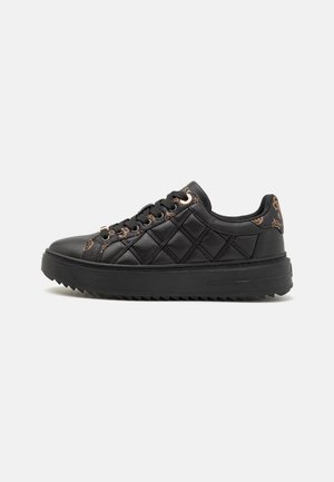 Sneaker in pelle nera con design trapuntato, punta rotonda, colletto imbottito e hardware dorato a contrasto. Suola in gomma nera spessa con scanalature.