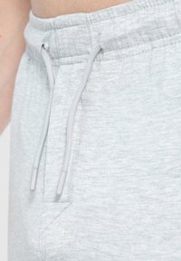 Hellgraue Jogginghose mit einer Kordelzugbund, ausgestattet mit zwei Taschen und einem weichen, strukturierten Stoff.