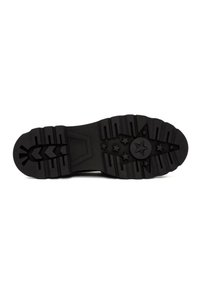 Suela de zapato de goma negra con patrón de agarre texturizado, que presenta diseños de estrellas y rayas. Material duradero para una buena tracción.