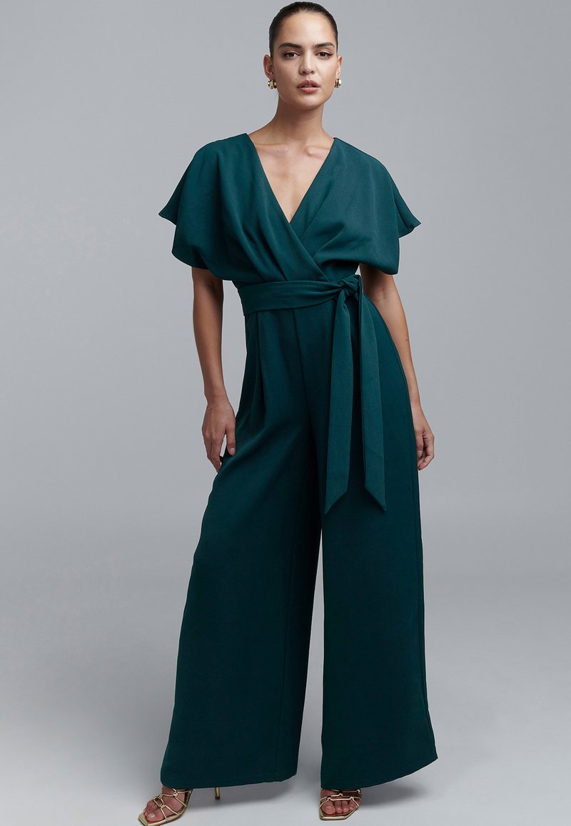 Teal wide-leg jumpsuit with a wrap design, short flutter sleeves, and a tied waist. Smooth fabric with a matte finish.
