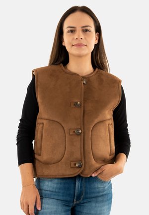 Gilet marrone in finta pelle scamosciata con scollo tondo, tre bottoni di chiusura e due tasche frontali. Indossato sopra una camicia nera a maniche lunghe.