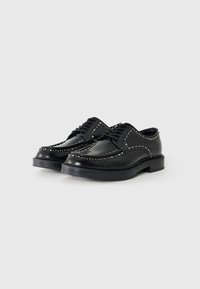 Black leather shoes with a smooth texture, featuring studded accents along the edges and a sturdy flat sole. Classic lace-up design.