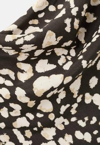 Czarny materiał z rozmieszczonym wzorem zwierzęcym w kremowych i beżowych odcieniach, o miękkiej, teksturowanej powierzchni.