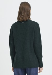 Pulover supradimensionat verde închis, cu o finisare moale și texturată. Prezintă un guler înalt și tiv ribat. Design simplu, minimalist.