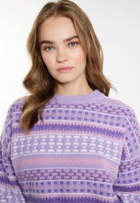 Pullover lavorato a maglia in tonalità di lavanda e rosa, caratterizzato da motivi geometrici. Texture morbida con scollo a rondine e vestibilità rilassata.
