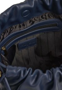 Granatowa skórzana torebka typu bucket z czarną satynową podszewką, kieszenią na zamek oraz etykietą "Pepe Jeans". Zmarszczona górna część.