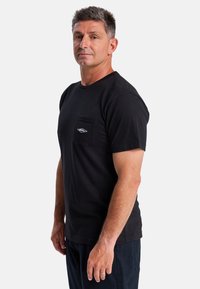 Zwarte katoenen t-shirt met korte mouwen, voorzien van een linkse borstzak en een klein logo-detail; comfortabele pasvorm en klassieke ronde hals.