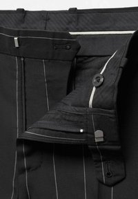 Pantaloni neri su misura con una sottile riga bianca. Le caratteristiche includono una cerniera frontale, chiusura con bottone e dettagli in tessuto interno.