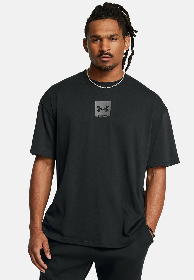 Sort kortærmet t-shirt lavet af bomuld. Har et kvadratisk gråt logo på brystet. Enkel design, afslappet pasform og blød tekstur.