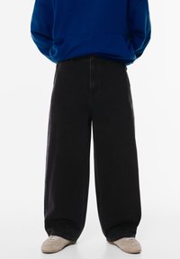 Sorte bredbenede jeans med høj talje, lavet af denimstof. Har lige ben, en knaplukning foran og diskrete syninger.