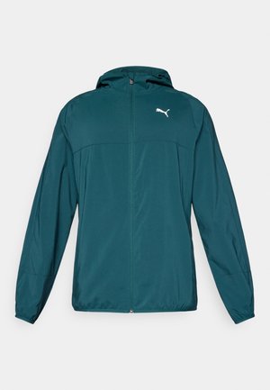 Casaco leve em azul petróleo com capuz, fecho éclair completo e logótipo branco no peito. Textura suave com punhos e bainha elásticos.