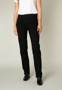 Zwarte spijkerbroek met een rechte pasvorm, uitgerust met een klassieke vijf-pocket ontwerp en riemlussen, gecombineerd met zwarte enkellaarsjes.