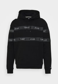 Svart huvtröja med grå horisontella ränder som har texten "TOMMY" och "JEANS", framfickor för känguru och ribbade ärmslut.