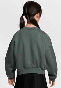 Sweat-shirt vert avec une coupe décontractée, col rond et poignets côtelés. Tissu doux au toucher lisse ; il possède un ourlet froncé.