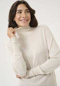 Cremfarbener Rollkragenpullover mit langen Ärmeln, weichem Material und lockerer Passform. Mit hohem Kragen und gerippten Bündchen.
