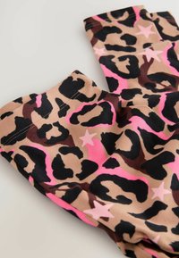 Leggings mit Leopardenmuster, die einen beigen Hintergrund mit schwarzen und pinken Leopardenflecken und Sternakzenten aufweisen; aus weichem, dehnbarem Stoff gefertigt.
