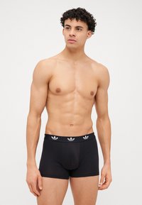 Schwarze Baumwoll-Boxershorts mit elastischem Bund, verziert mit weißen drei Streifen des Adidas-Logos, körpernahe Passform und glatte Textur.