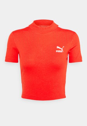 Punane ribaga lühikeste varrukatega ülikond kõrge kaelusega ja valge Puma logo vasakul rinnaosal; vormitud disain tekstuuriga kangast.