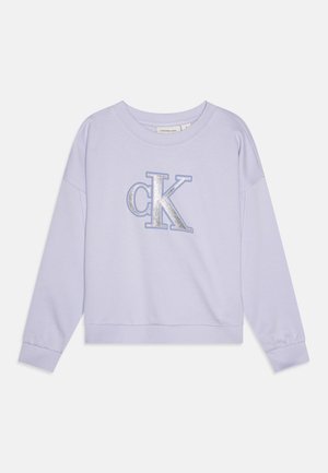 Lavender sweatshirt with a crew neck and dropped shoulders, featuring a silver glitter "ck" logo on the front. Soft fabric and ribbed cuffs.