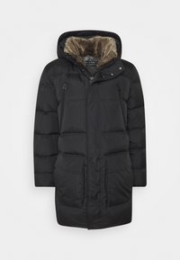 Sort polstret jakke med hætte, der har fuskepelsfor, to forlommer og lynlåse. Glat tekstur og langt design for ekstra varme.