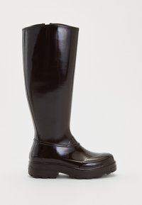 Botas de lluvia negras brillantes hasta la rodilla, con suela gruesa y con tacos, puntera redondeada y costuras decorativas mínimas.