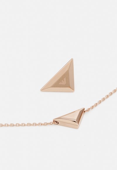 Náušnice ve tvaru trojúhelníku z růžového zlata s lesklým kovovým povrchem, zdobené malým vyrytým logem a jemným spojením na řetízku.