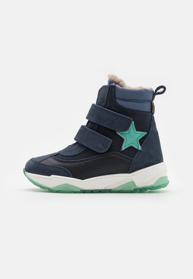 Mörkblå barnstövel med två kardborreband, mjuk pälsfoder, ljusblå detaljer, grön stjärna och en vit och grön sula.