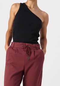 Svart en-sidig ribbad t-shirt som kombineras med lösa bordeauxbyxor med dragsko i midjan och framfåll.