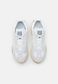 Vita och ljusgråa träningsskor med mocka och meshmaterial, med rundad tå, snörning fram och gummisula.