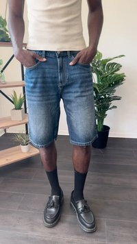 Keskmise sinise pesu teksased lühikesed püksid, põlveliigini, sirge lõikega, koos mustade loaferite ja pahkluu sokkidega. Aluseline valge ribaga tanktop.