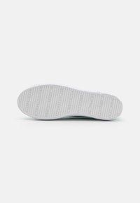 Biała podeszwa sneakerów z teksturowanym wzorem, z poziomymi rowkami i wytłoczonym logo marki w różnych miejscach. Czyste i gładkie wykończenie.