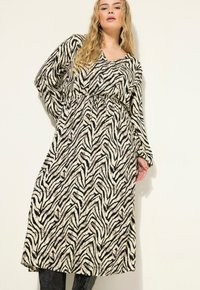Langarm jurk met een V-hals, voorzien van een zwart en crèmekleurig zebrapatroon. Gemaakt van een gestructureerde stof, om de taille aangetrokken voor een flatterende pasvorm.