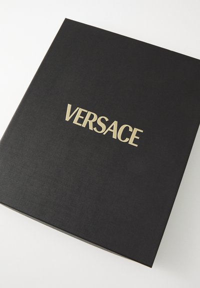 Juodas kietas aplankas su tekstūruota paviršiumi ir auksiniu "VERSACE" logotipu, esantis centre ant priekio. Minimalistinis dizainas, kvadratinė forma.