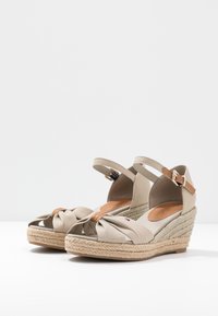 Sandali d'ebano color beige con suola in juta intrecciata, tessuto annodato sulla punta e cinturino alla caviglia color nocciola con fibbia dorata.